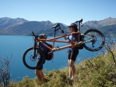 Dad and Anna Portaging tandem through scrub by lake wakatipu
